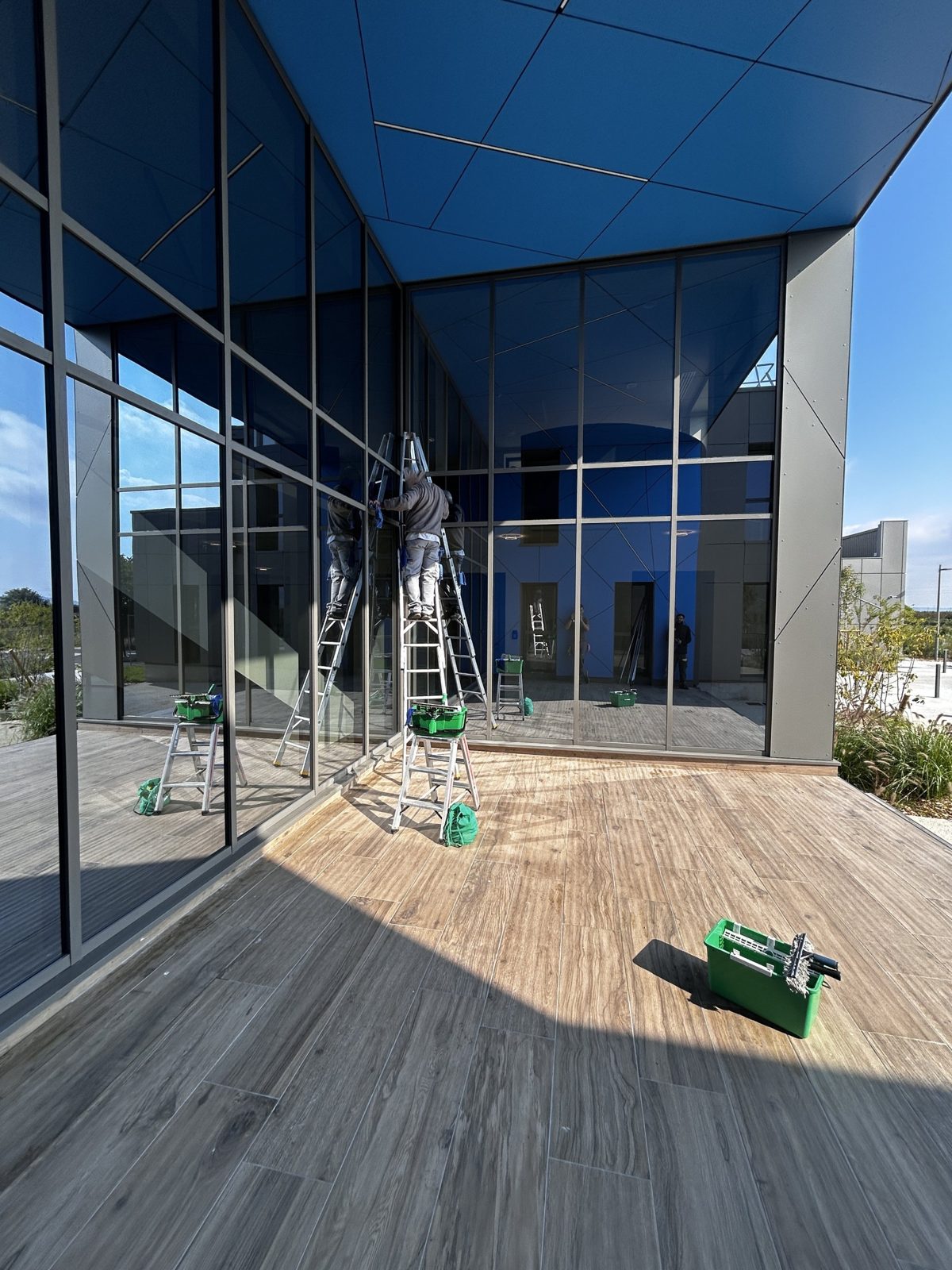 Lavage d'une façade vitrée grande hauteur à l'échelle sur un bâtiment professionnel